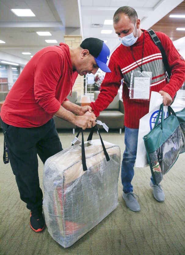 Aftab Afridi (left) pries the fingers of Shakil Safi so that he can carry Safi's luggage Oct. 29 at The Eastern Iowa Airport.