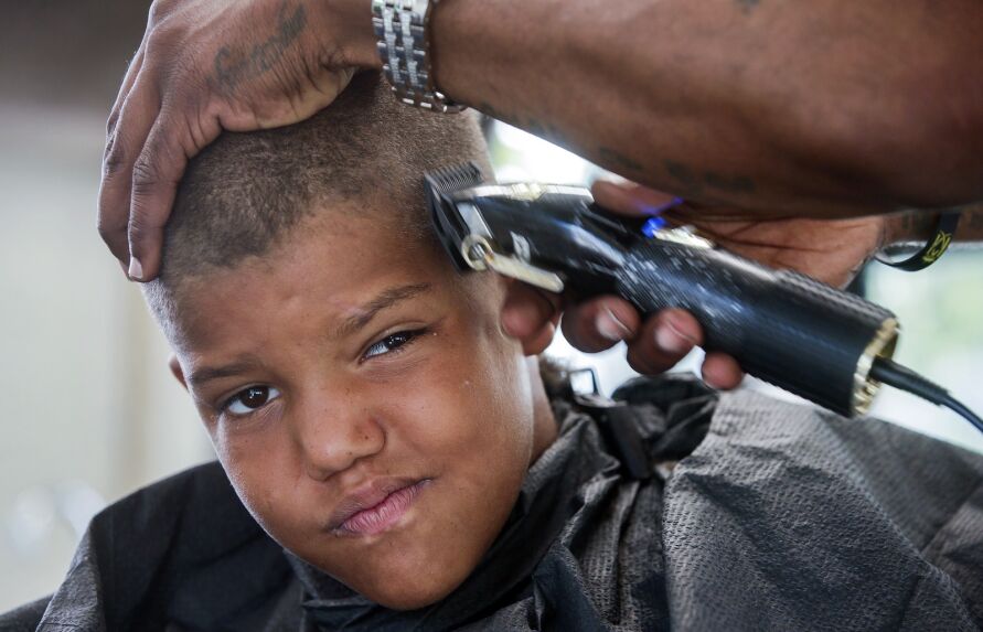 William Burt, founder and owner of Kut Kings in Waterloo, cuts the hair of Travonte Davis, 10, on June 14 in his mobile barbershop in the parking lot at Westminster Presbyterian Church in southeast Cedar Rapids.