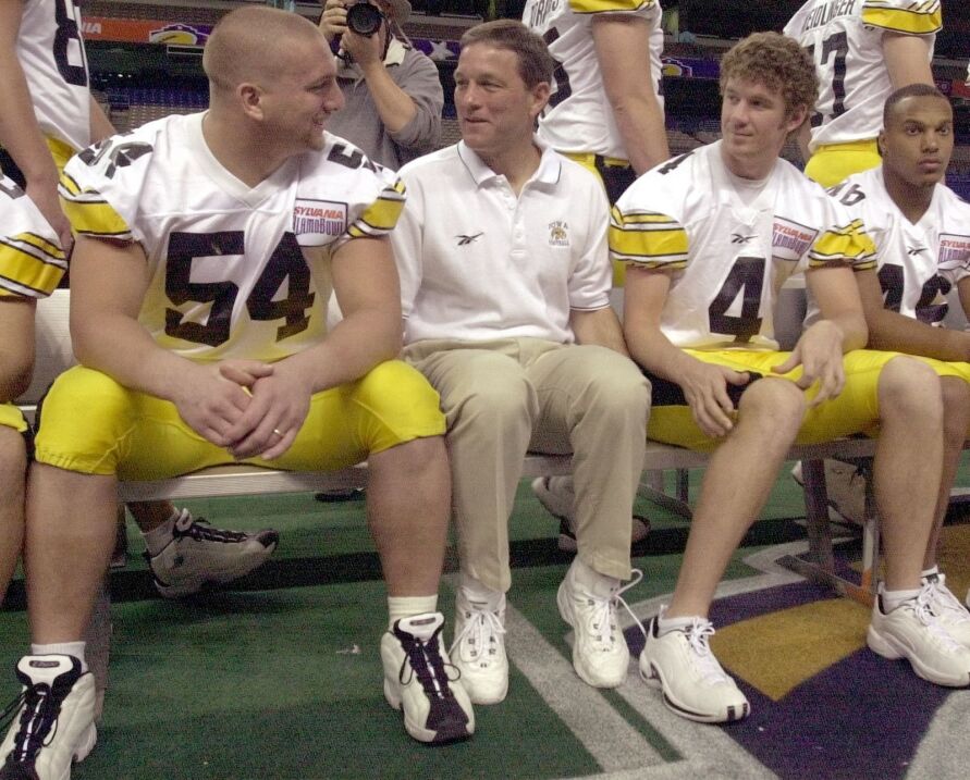 Iowa football coach Kirk Ferentz talks with senior defensive end Aaron Kampman (54) and senior quarterback Kyle McCann (4) as senior running back Ladell Betts (46) looks on before the team's photo is taken the day before the 2001 Alamo Bowl.